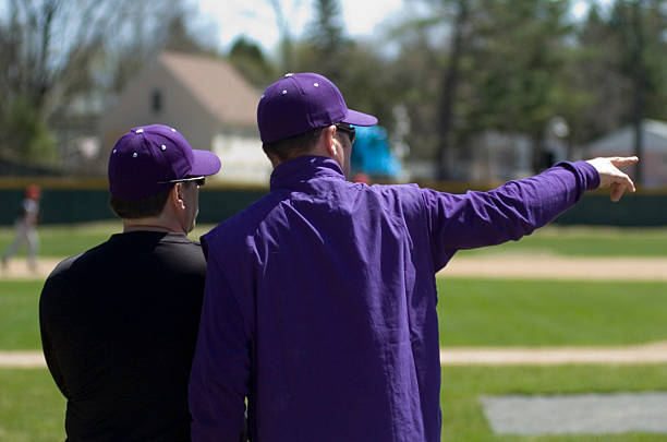 Baseball Coach talking to assistant while pointing to field in background