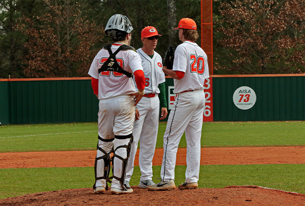 Tim Fanning in white uniform has a meeting at the pitchers mound with his pitcher and catcher