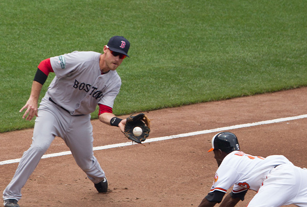 Red Sox third baseman catching ball to tag a sliding Orioles player at third base