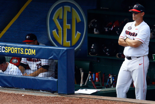 Georgia head coach Scott Stricklin in white jersey standing on dugout steps looking out onto field