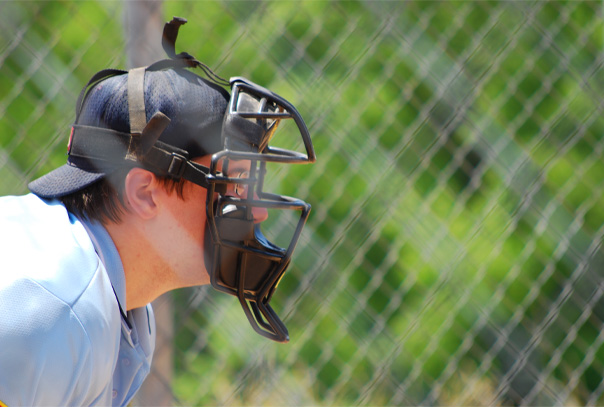 Side profile of umpire behind home plate wearing umpire catcher's style face mask