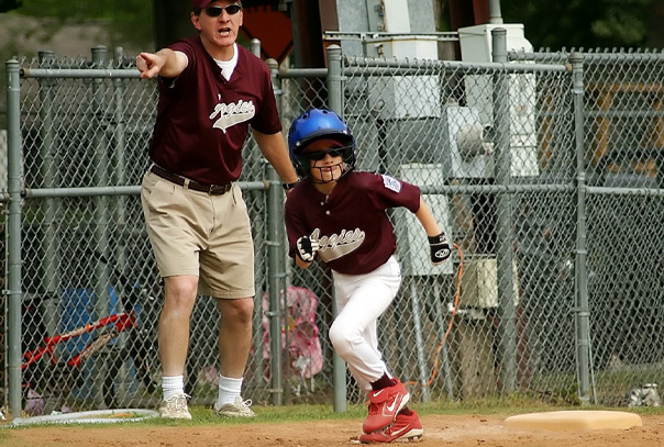 A youth baseball player heading home from third