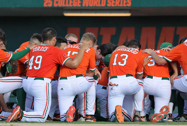 University of Miami baseball team on a knee in a huddle