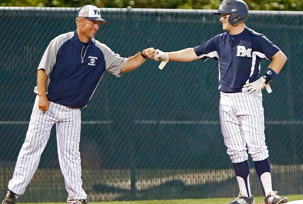 A Coach fist bumping his player on base