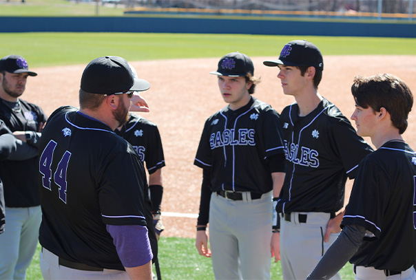 Griffin Tate talking with several of his players on the field.