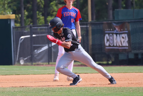 A high school age baseball player running with his head down trying to steal second base