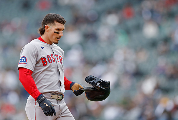 Jarren Duran in Red Sox away uniform holding his helmet walking off field.