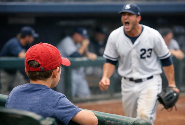 Kid in red ballcap looking at a player walking off the field yelling what appears to be an obscenity